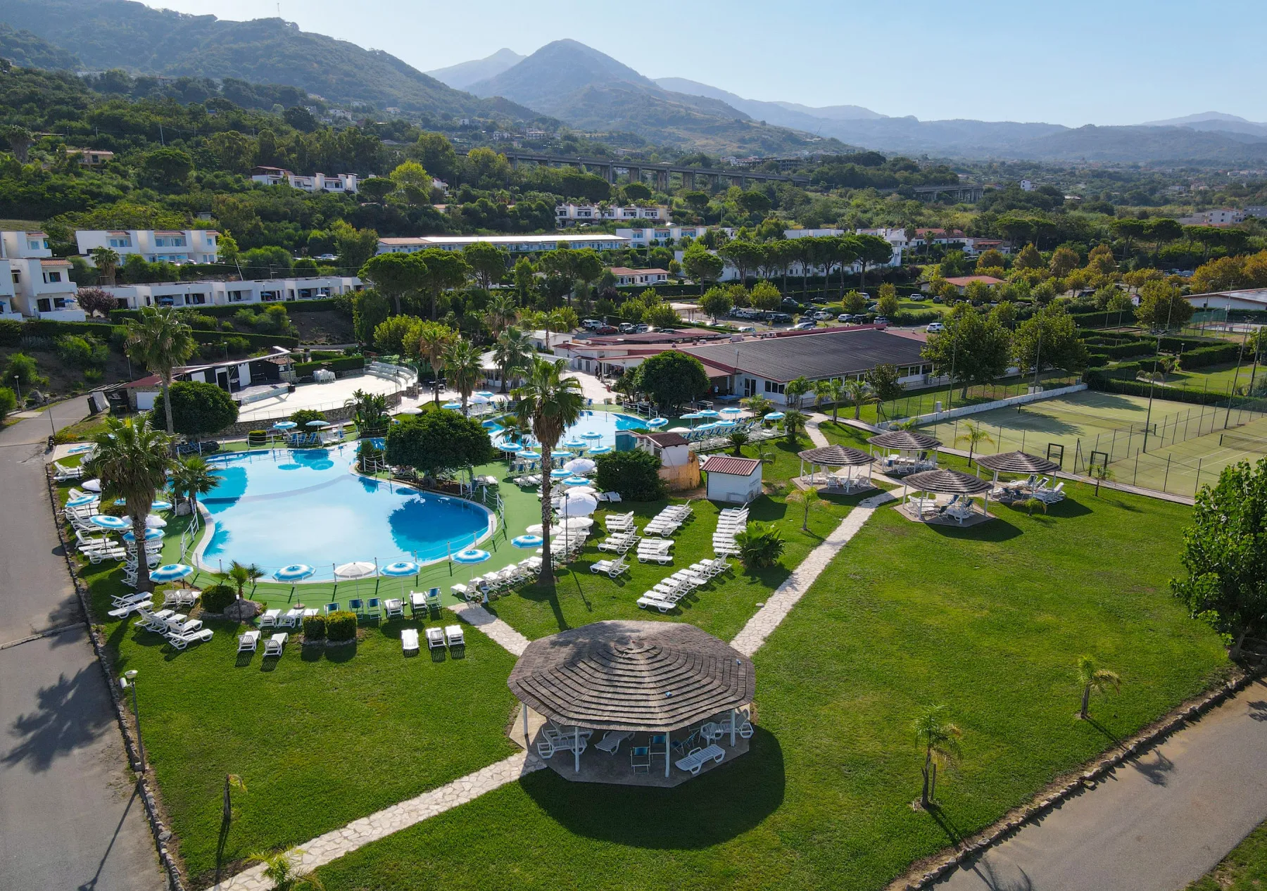 Veduta aerea del complesso con grande piscina, lettini e montagne sullo sfondo