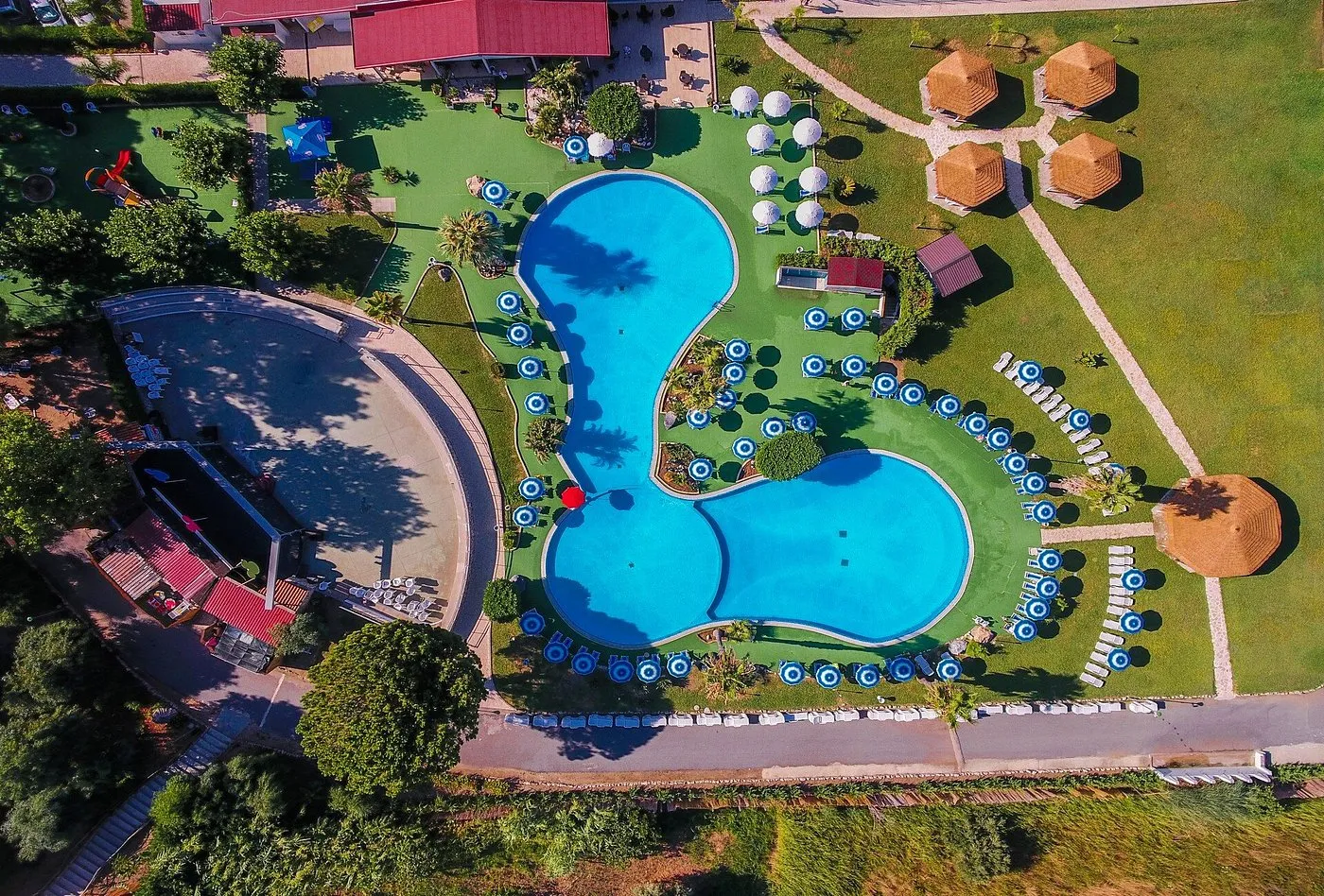 Vista aerea della piscina a forma sinuosa con ombrelloni e area spettacolo