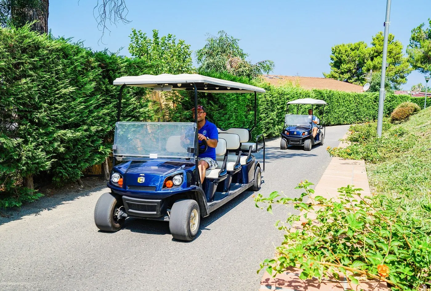 Golf cart blu lungo il viale alberato del resort per il trasporto interno