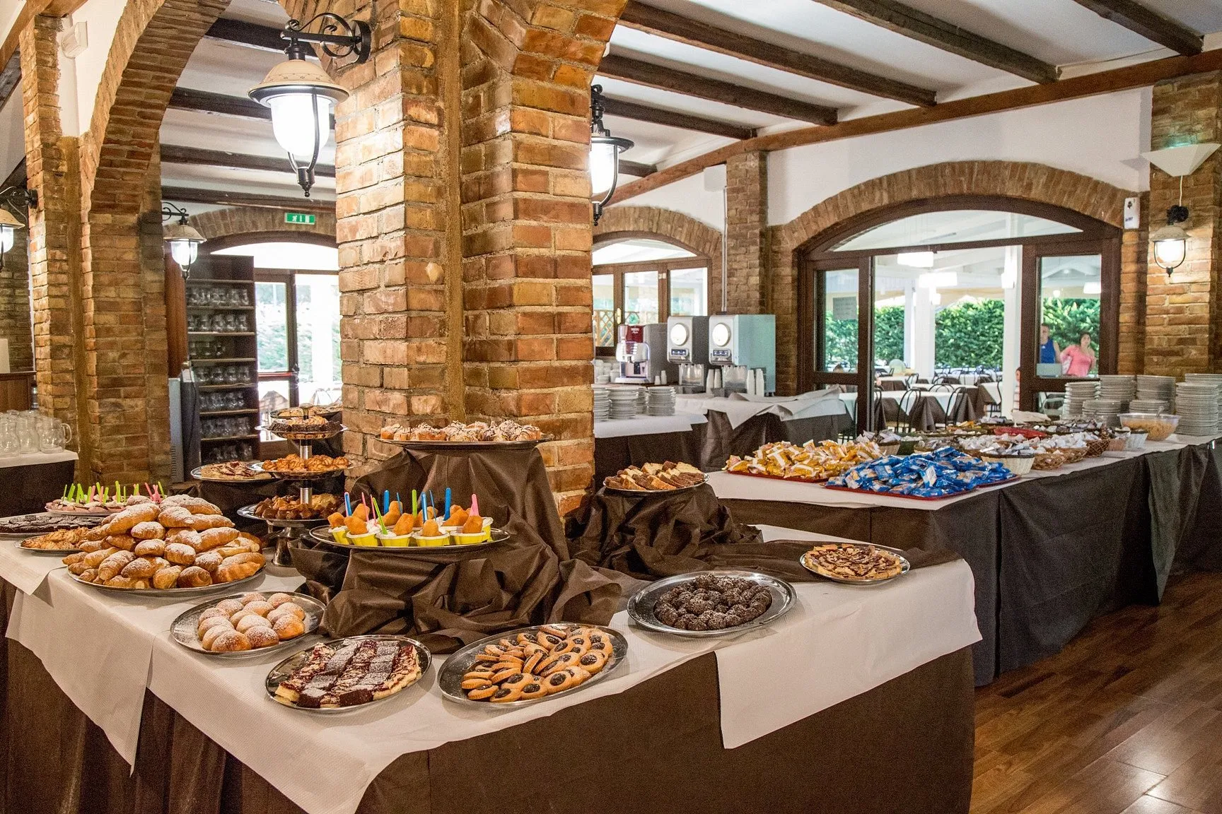 Buffet di dolci e pasticceria nella sala ristorante con archi in mattoni