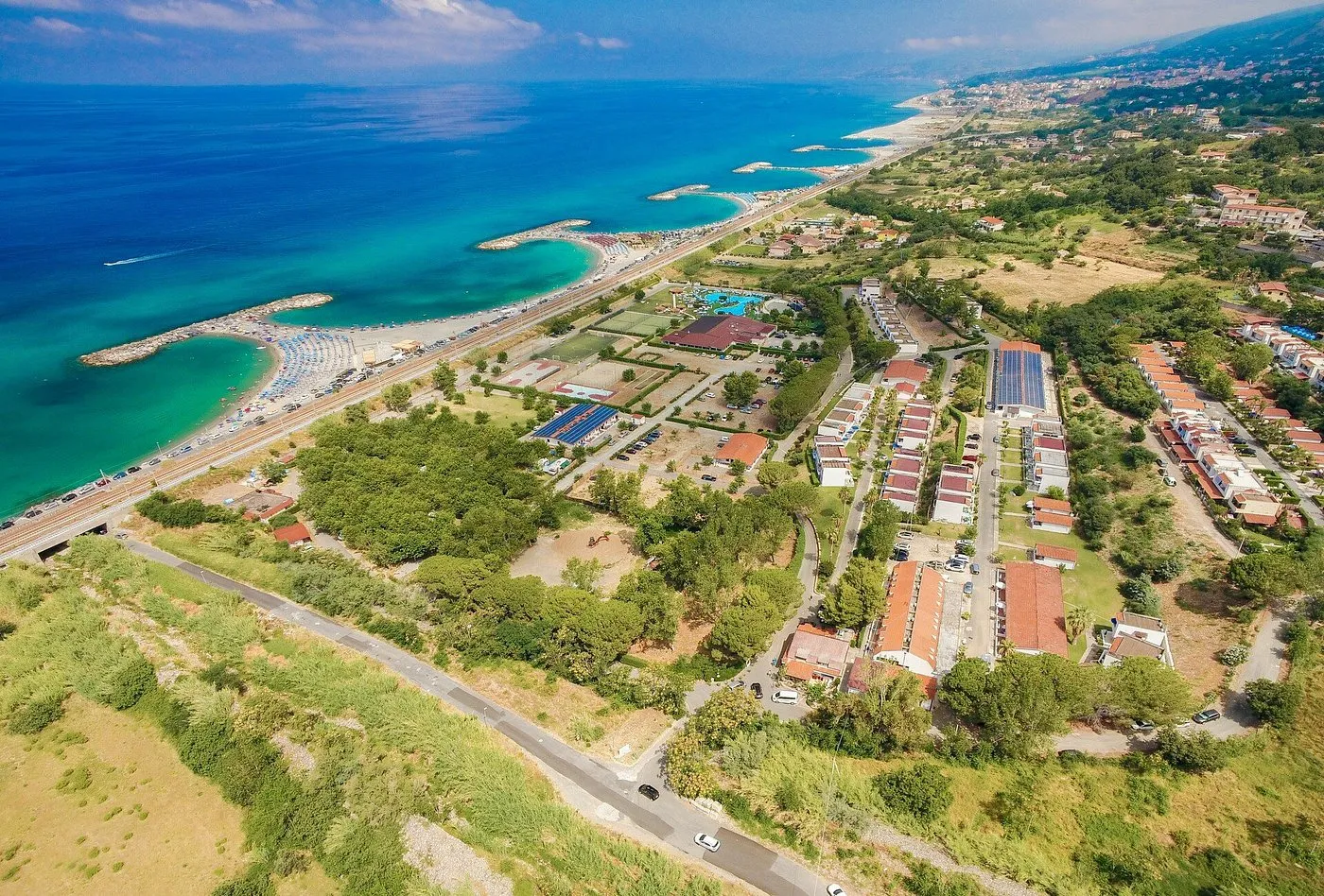 Veduta aerea della costa con resort, spiaggia e mare turchese tra il verde