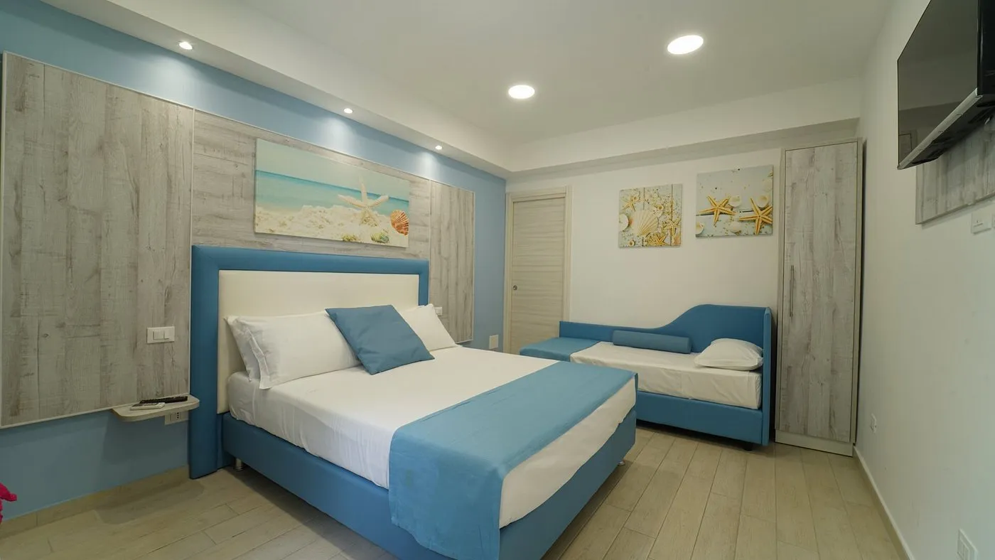 Camera matrimoniale con letto e divanetto in tonalità azzurre e parete in legno