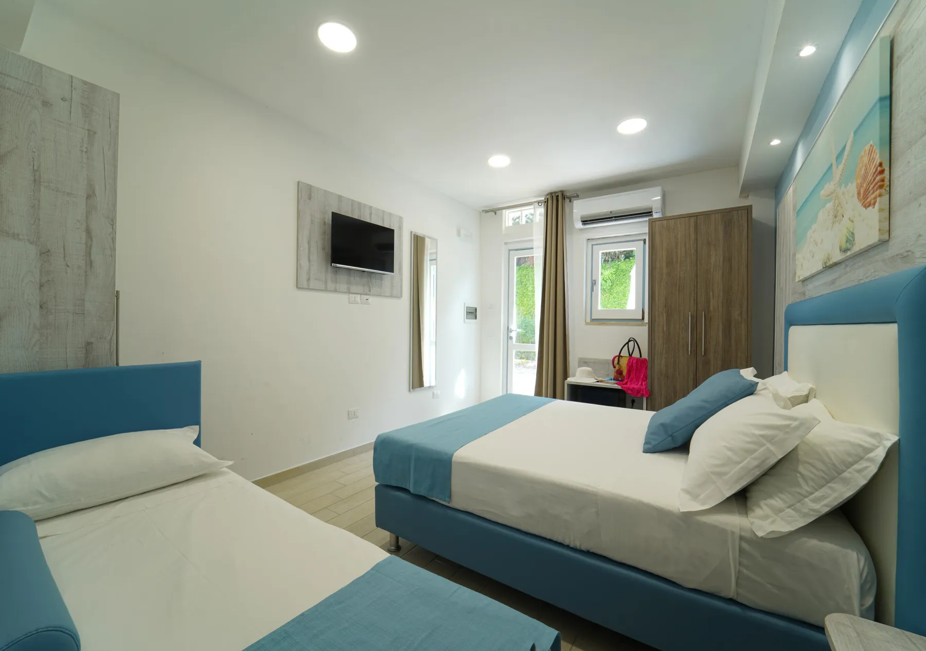 Camera con letto matrimoniale e singolo, TV e armadio in stile marino
