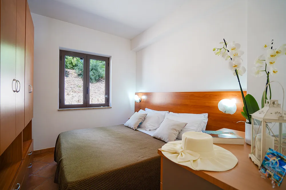 Camera da letto matrimoniale con armadio in legno e vista sulla collina