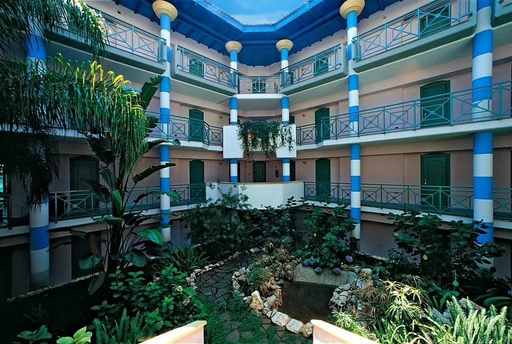 Cortile interno con colonne blu e bianche, ballatoi e giardino verde