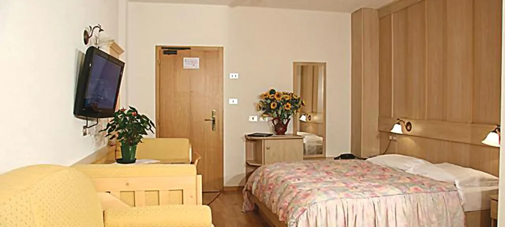 Camera con letto matrimoniale, TV a parete, divano e armadio in legno
