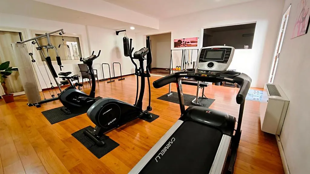 Palestra attrezzata con tapis roulant, cyclette ed ellittica su pavimento in parquet