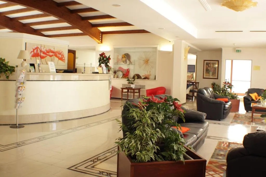 Reception dell'hotel con bancone curvo, divani in pelle e piante decorative