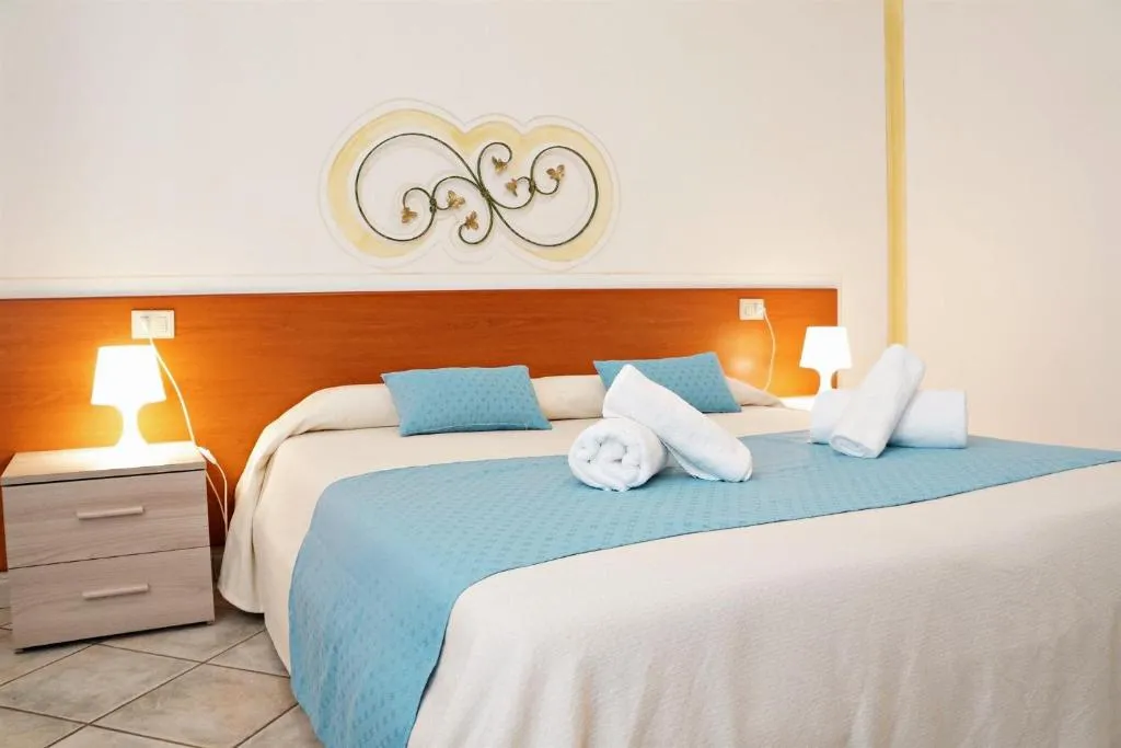 Camera da letto luminosa con letto matrimoniale, decorazione a parete in ferro battuto e asciugamani