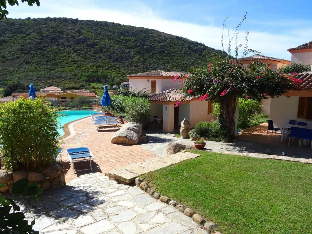 Giardino e vialetto in pietra con piscina e bouganville fiorita davanti alle case