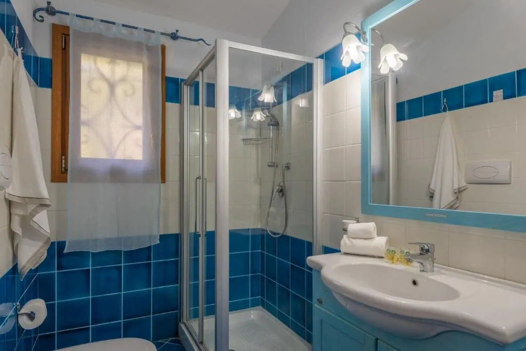 Bagno con piastrelle azzurre e bianche, doccia, lavabo e specchio