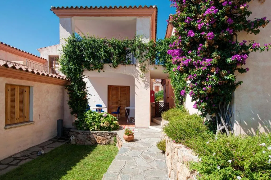 Ingresso di casa con bouganville fiorita, veranda e vialetto in pietra