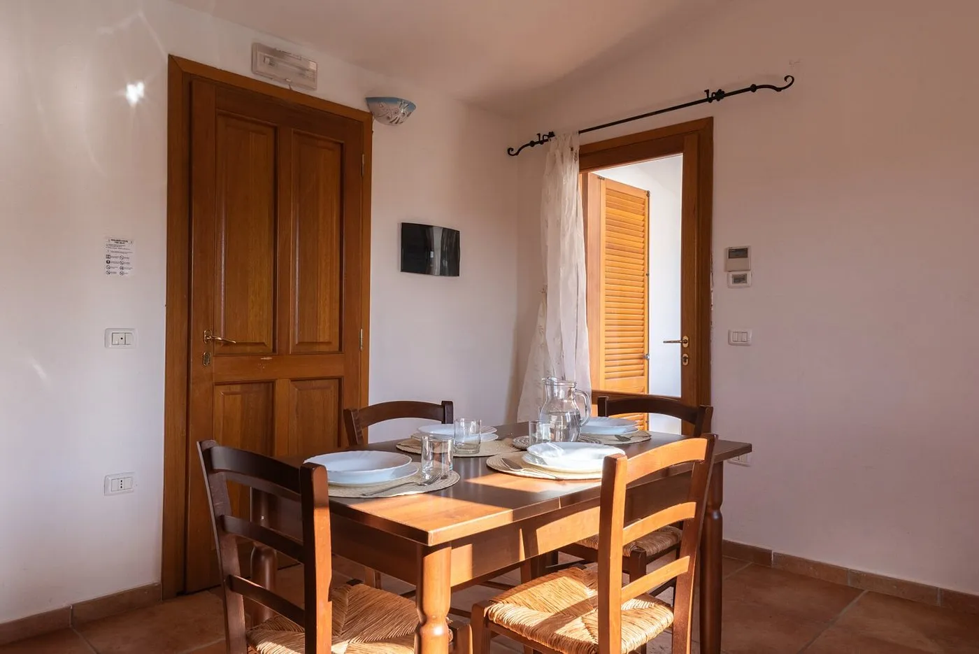 Zona pranzo con tavolo in legno apparecchiato e porte in legno