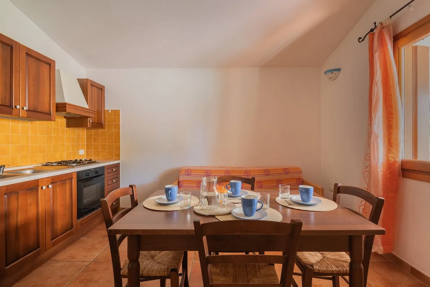 Cucina in legno con piastrelle gialle, tavolo da pranzo e divano