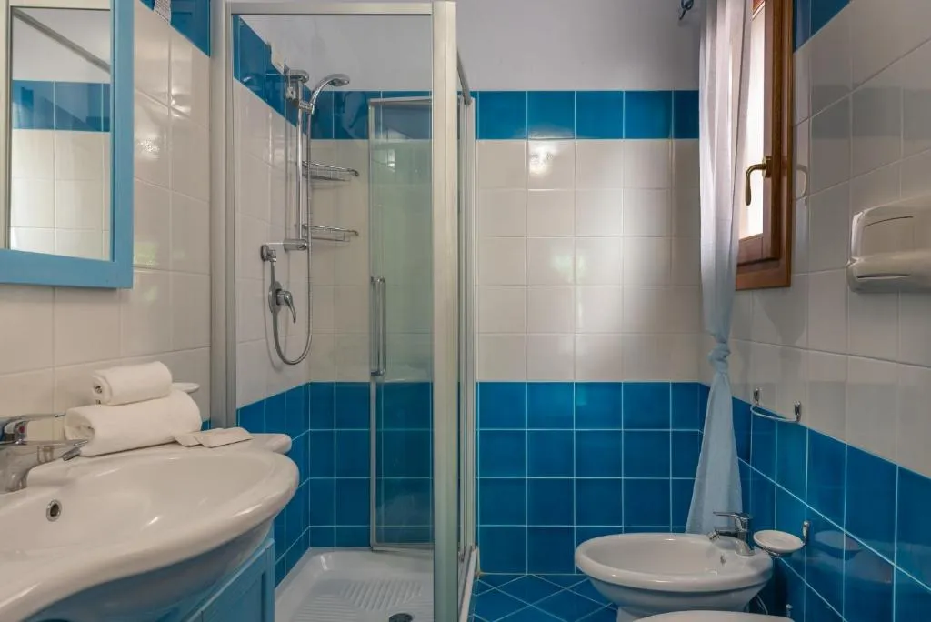 Bagno con piastrelle azzurre e bianche, doccia, lavabo, bidet e WC