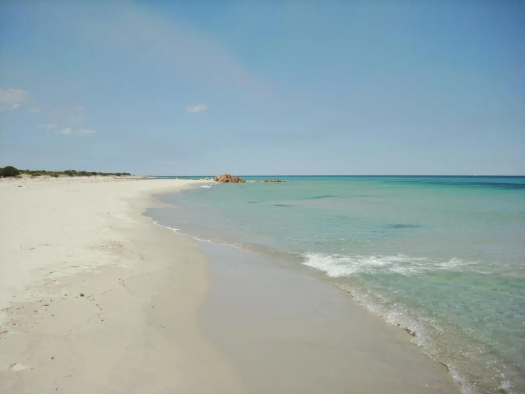 Spiaggia di sabbia bianca con mare turchese cristallino e scogli