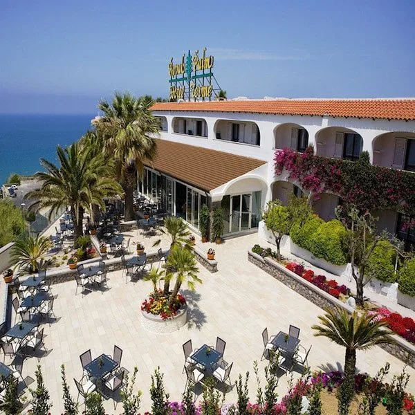 Facciata bianca del Royal Palm Hotel Terme con ampia terrazza, fiori e palme affacciata sul mare