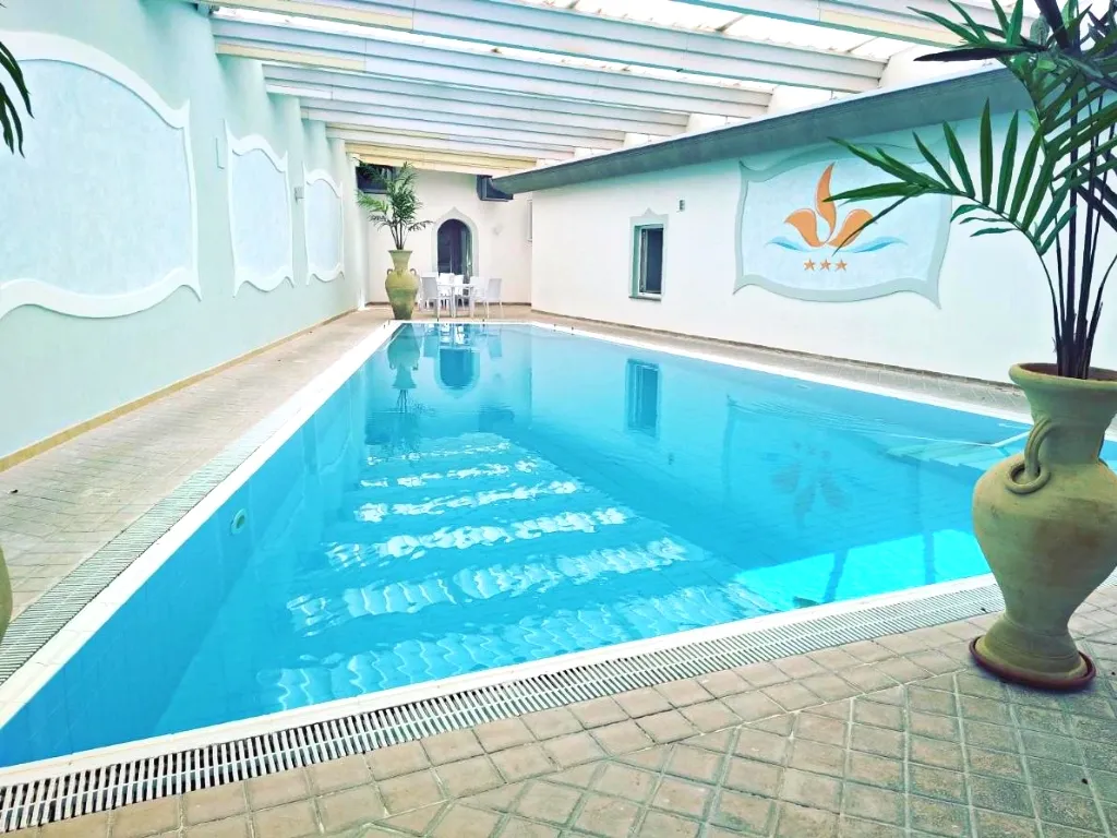 Piscina coperta interna con acqua azzurra e vasi in terracotta