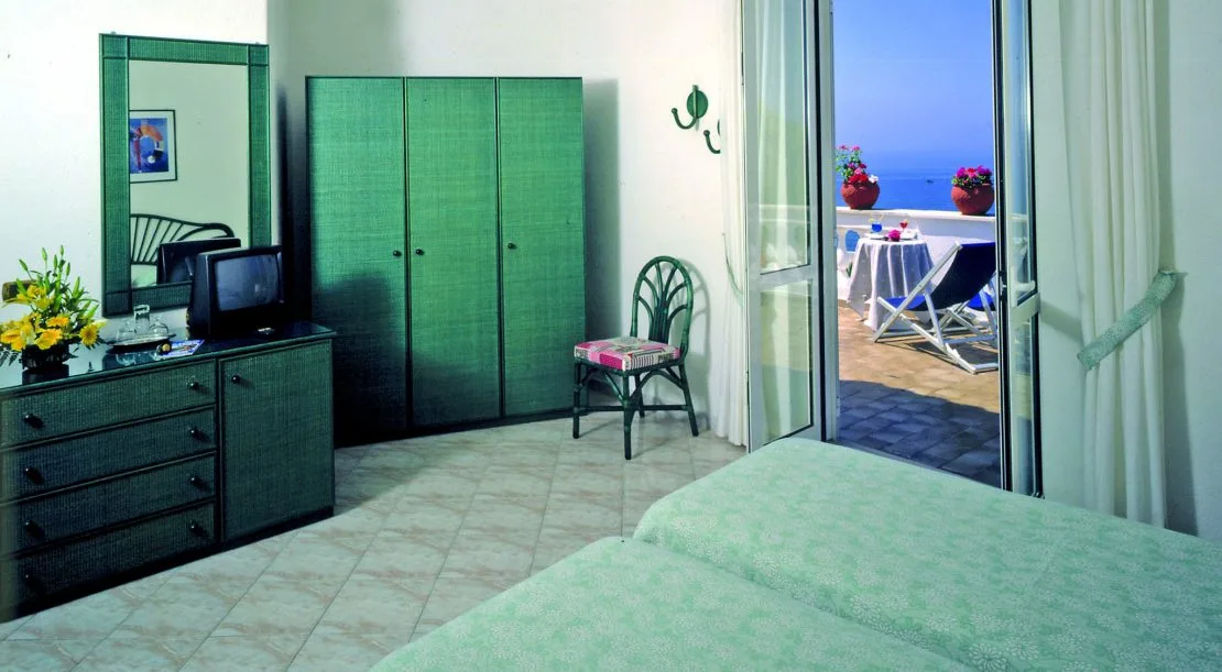 Camera con arredi verdi, armadio e terrazzo con vista mare