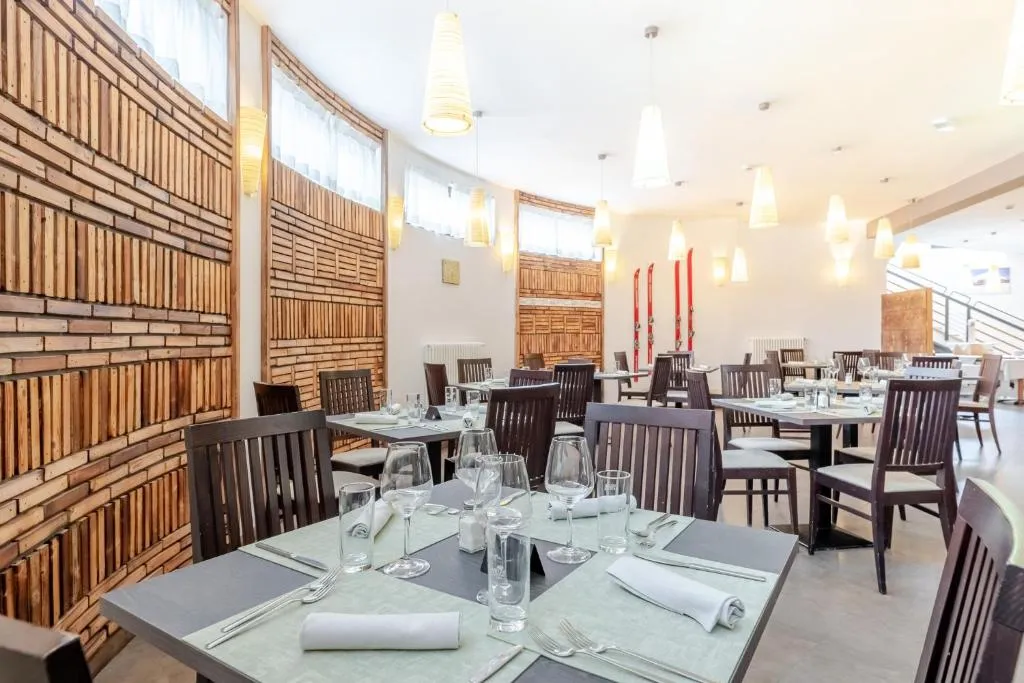 Sala ristorante luminosa con pareti in legno, tavoli apparecchiati e sci decorativi