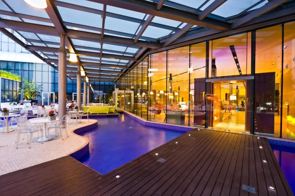 Patio coperto con piscina blu e tavoli bianchi al crepuscolo