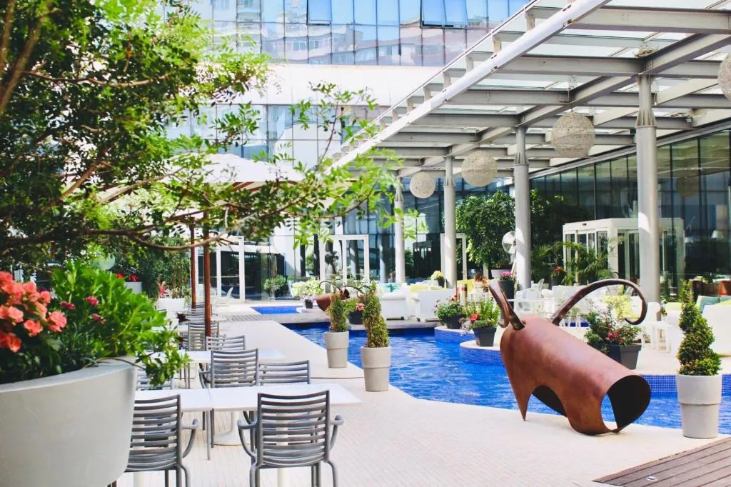 Terrazza giardino con piscina, vegetazione e scultura decorativa di giorno