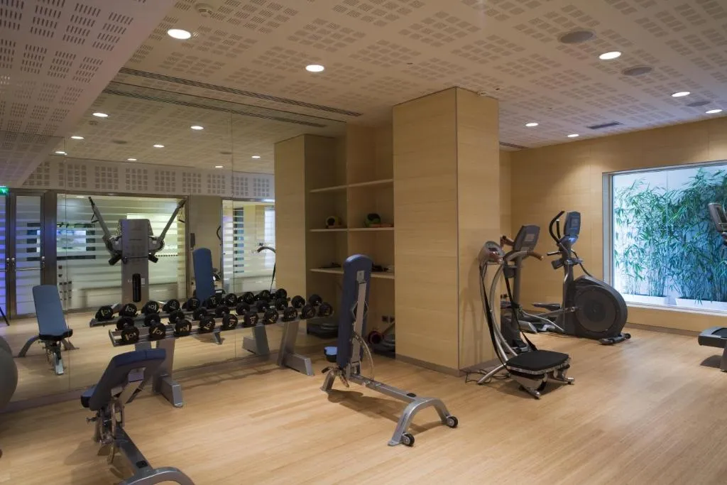 Palestra attrezzata con pesi, macchine cardio e pavimento in legno
