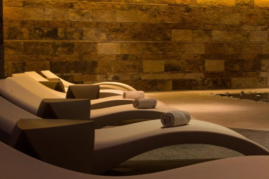 Lettini relax sagomati con asciugamani in area benessere dalla parete in pietra