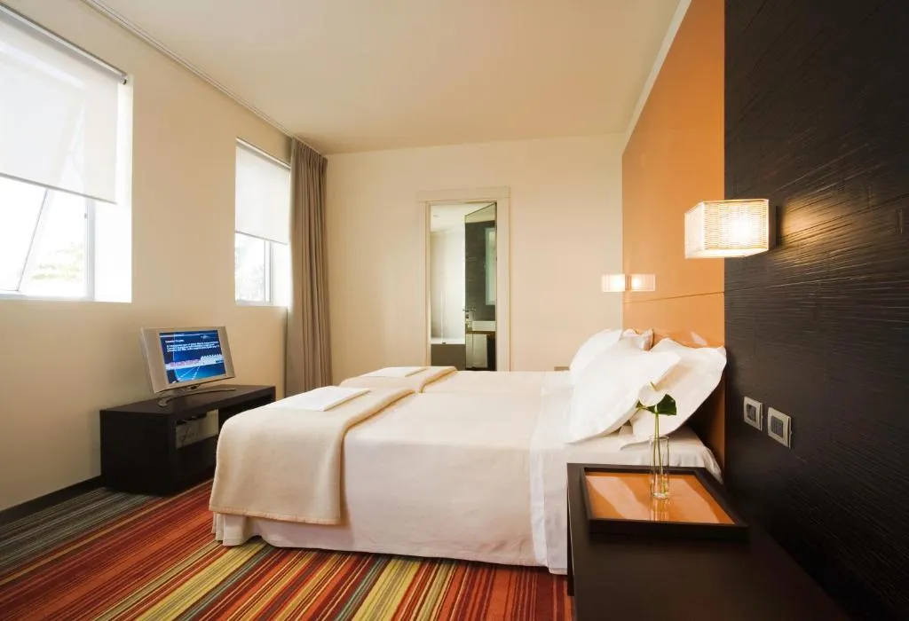 Camera con letto matrimoniale, TV e pavimento a righe colorate