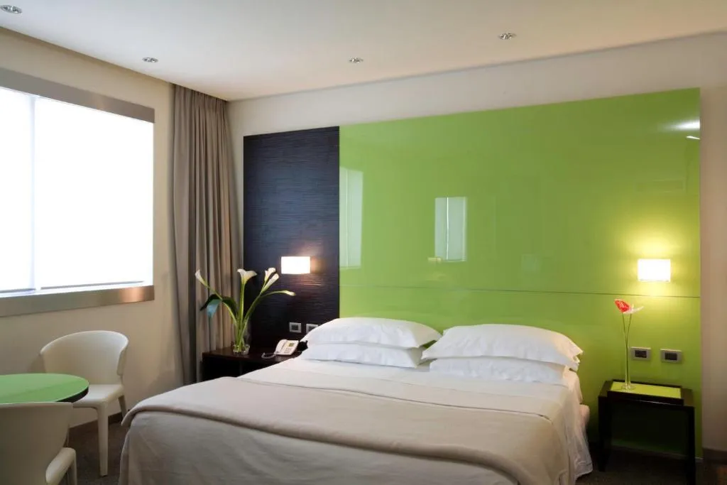 Camera con letto matrimoniale e parete decorativa verde lime