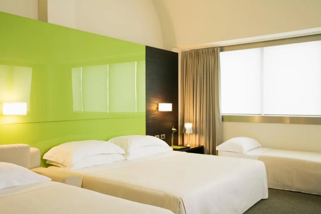 Camera tripla con letti, parete verde lime e ampia finestra