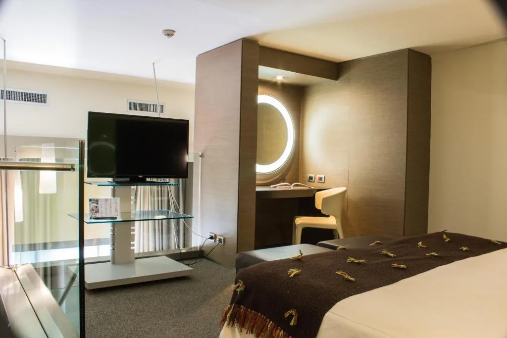 Camera con TV, scrivania con specchio rotondo illuminato e letto