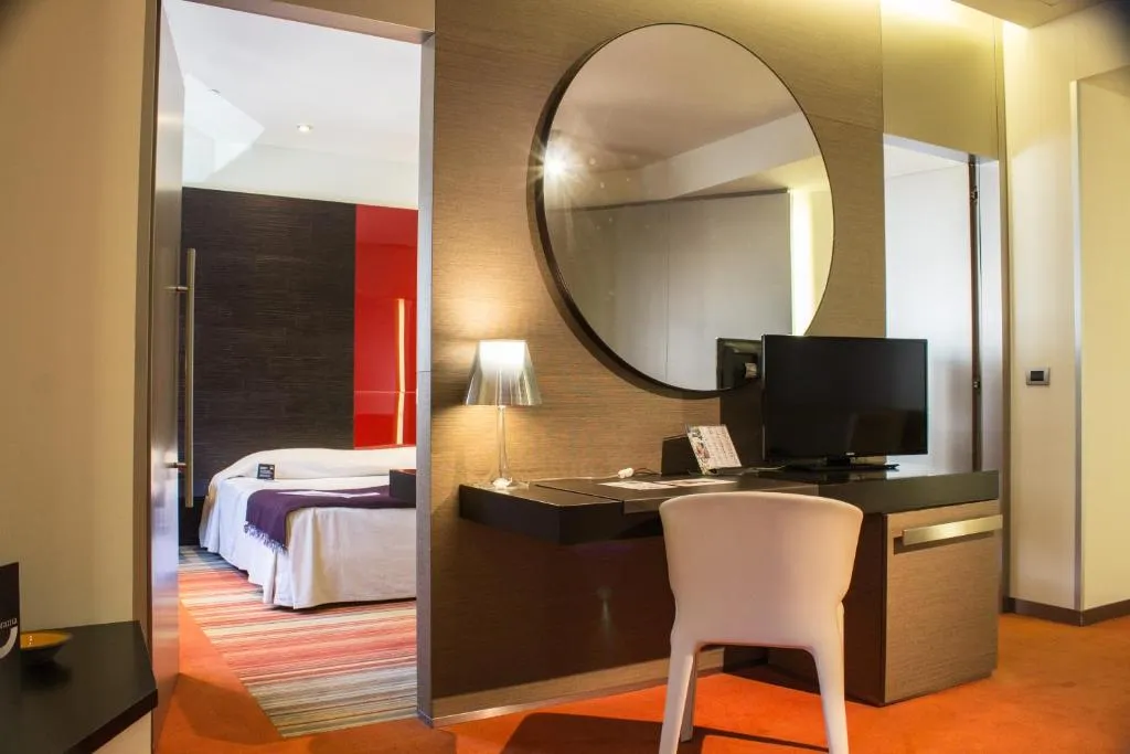 Suite con specchio rotondo, scrivania e camera da letto sullo sfondo