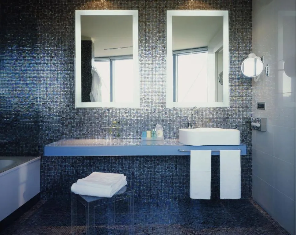 Bagno con mosaico blu, doppio specchio e lavabo appoggiato bianco