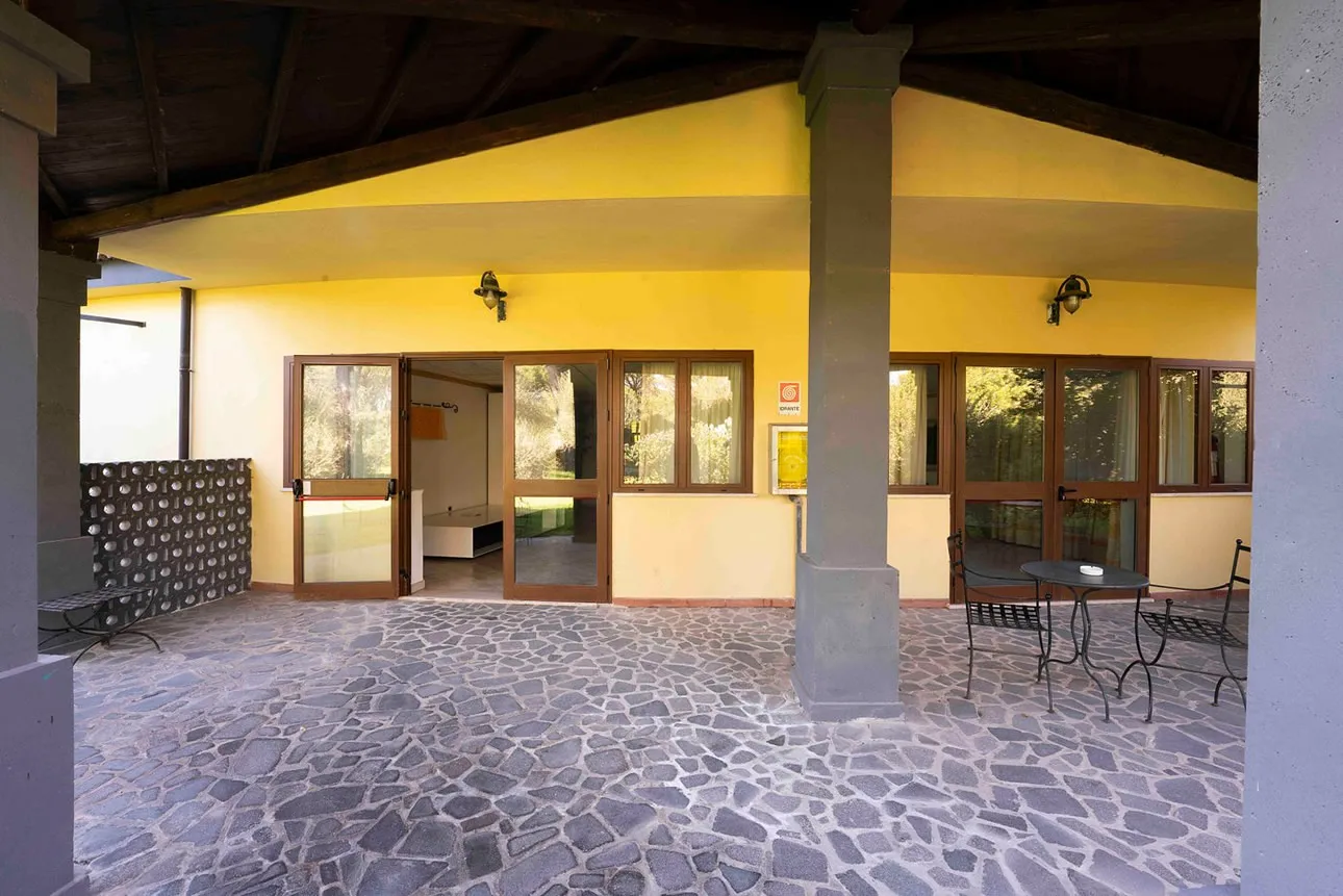 Portico con colonne e pavimento in pietra affacciato sulla vegetazione