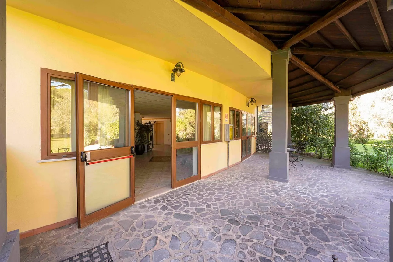 Porticato esterno con pavimento in pietra e pareti gialle affacciato sul giardino