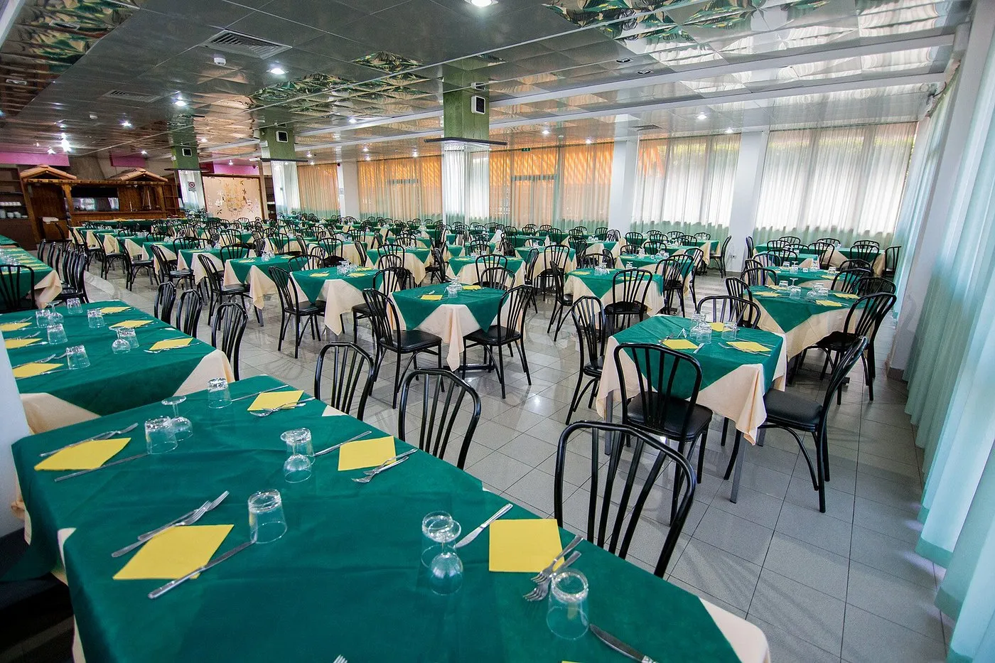 Buffet della colazione con struttura in legno, cornetti, salumi e cereali su tovaglia verde