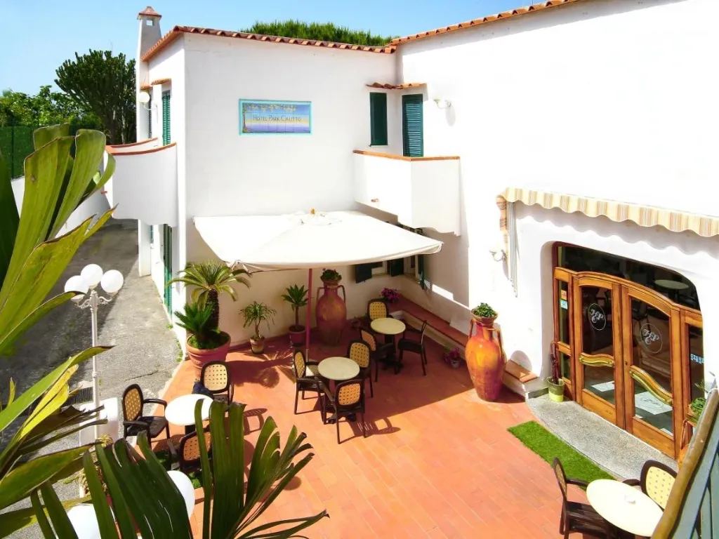 Terrazza esterna dell'Hotel Park Calitto con tavolini, ombrellone e ingresso in vetro