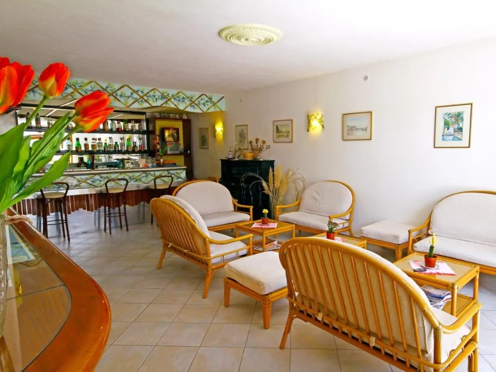 Hall dell'hotel con bar, poltrone in rattan e cuscini beige
