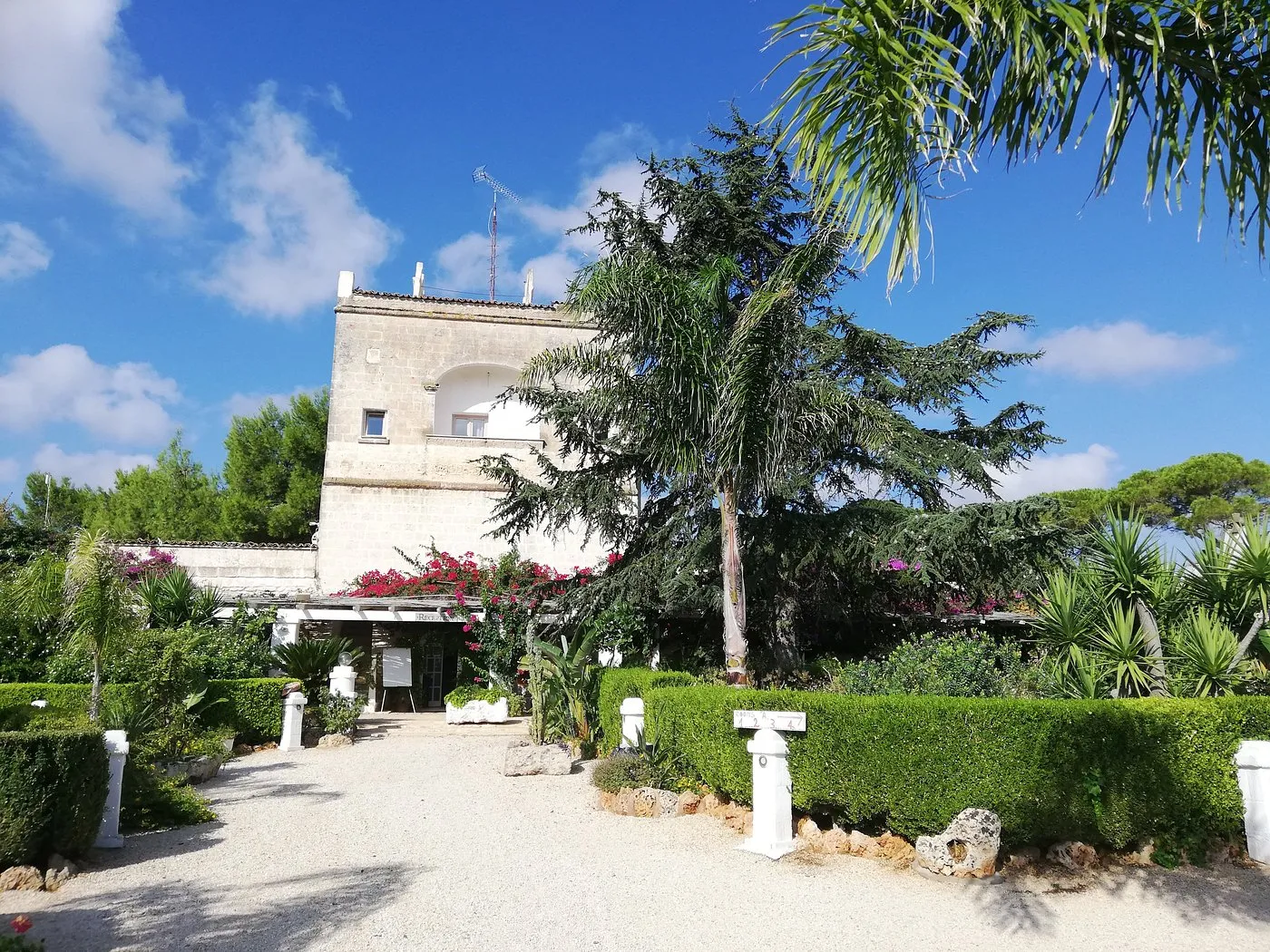 Ingresso della masseria con giardino fiorito e vegetazione mediterranea