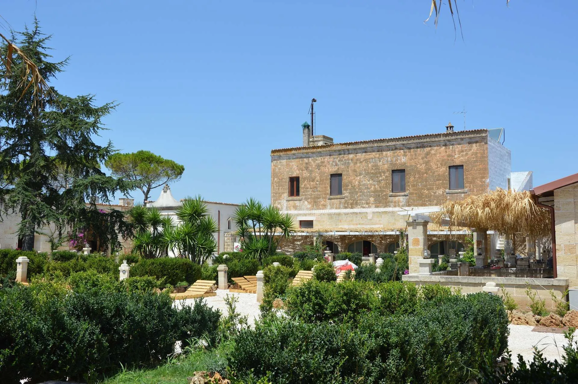 Vista della masseria storica con torre, giardino e area relax