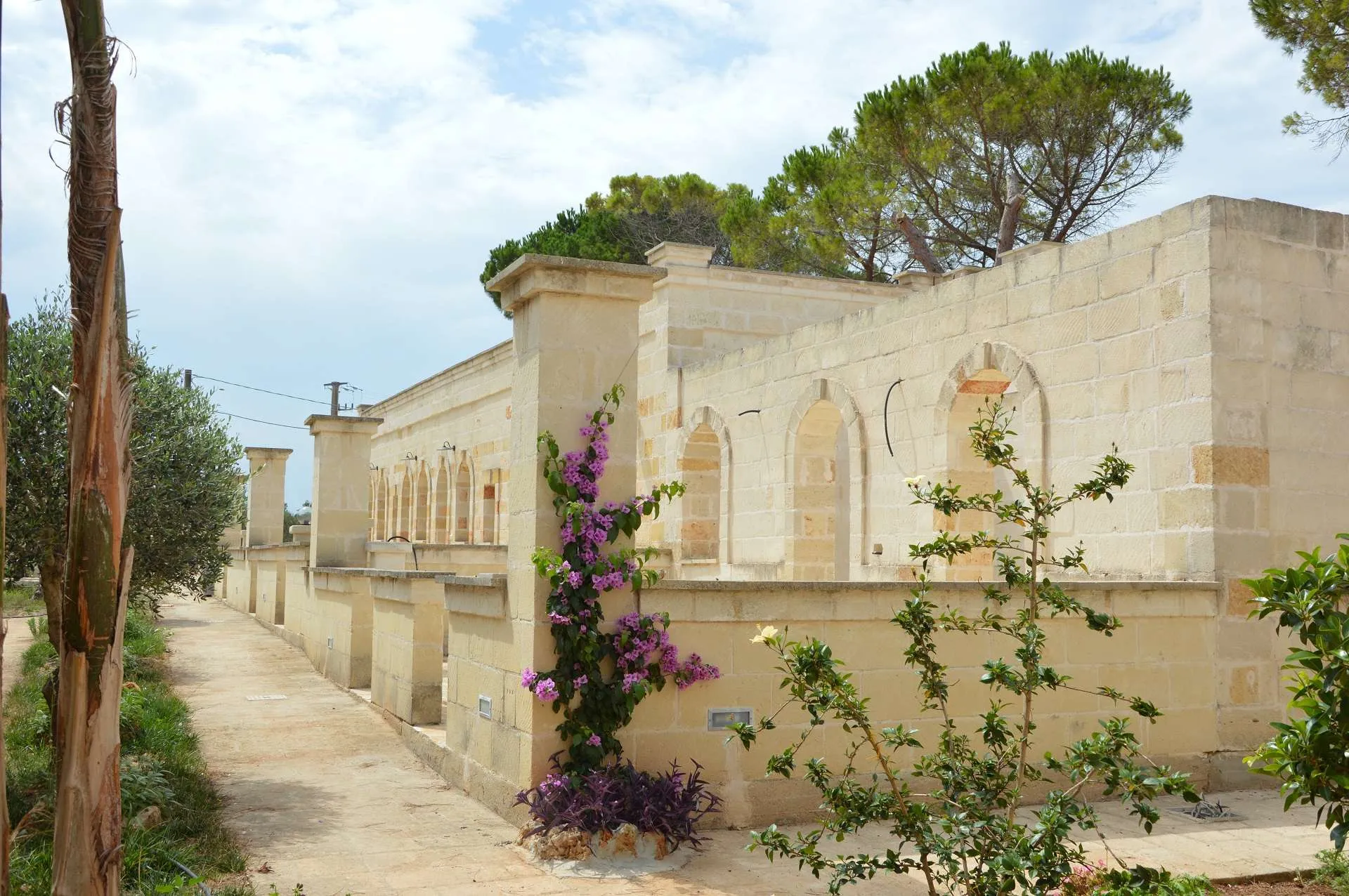 Facciata laterale in pietra con archi e bougainville