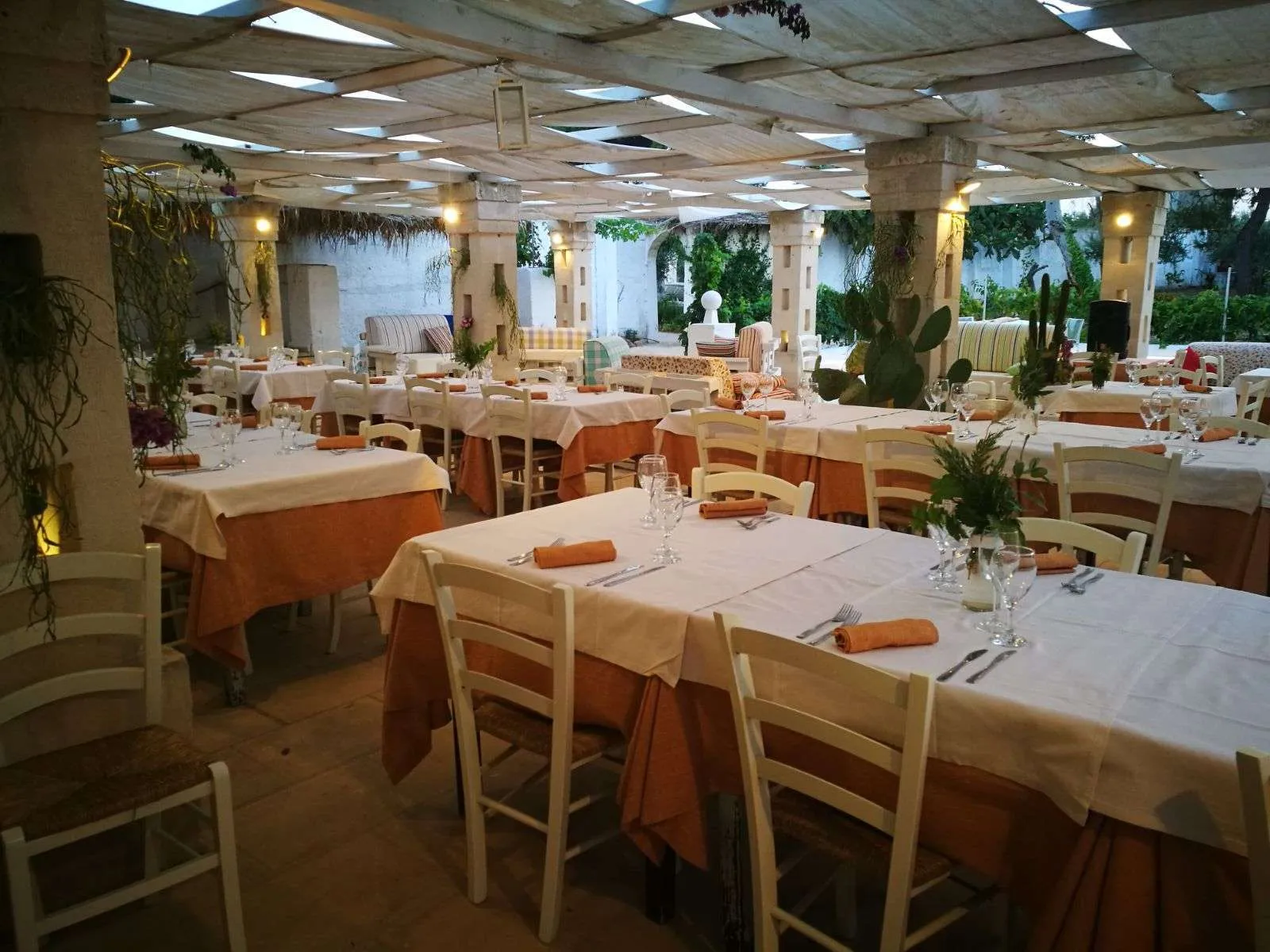 Ristorante all'aperto sotto pergolato con tavoli apparecchiati