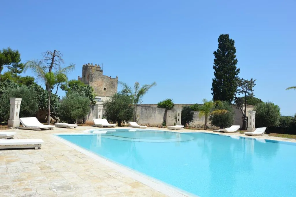 Piscina con lettini prendisole e torre storica sullo sfondo