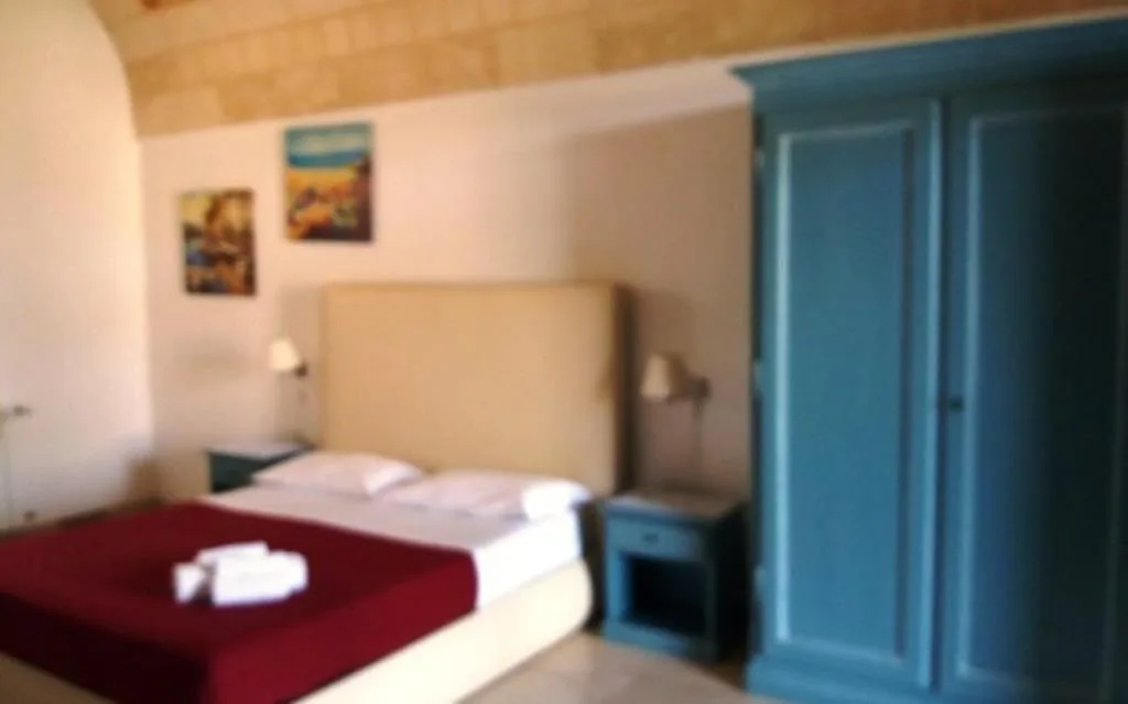 Camera con armadio azzurro, letto matrimoniale e quadri decorativi