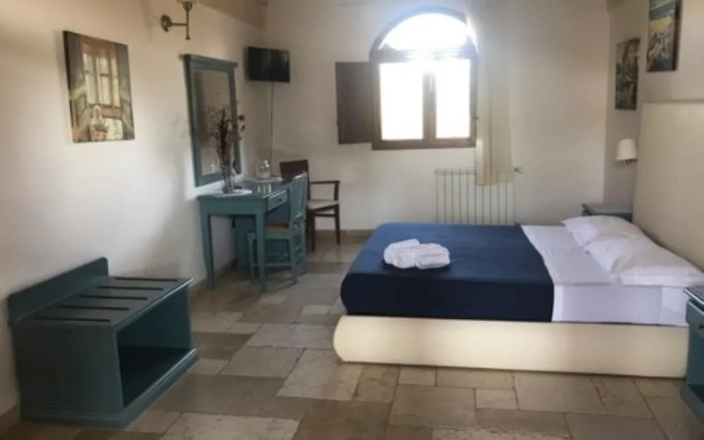 Camera con arredi turchese, scrivania e finestra ad arco