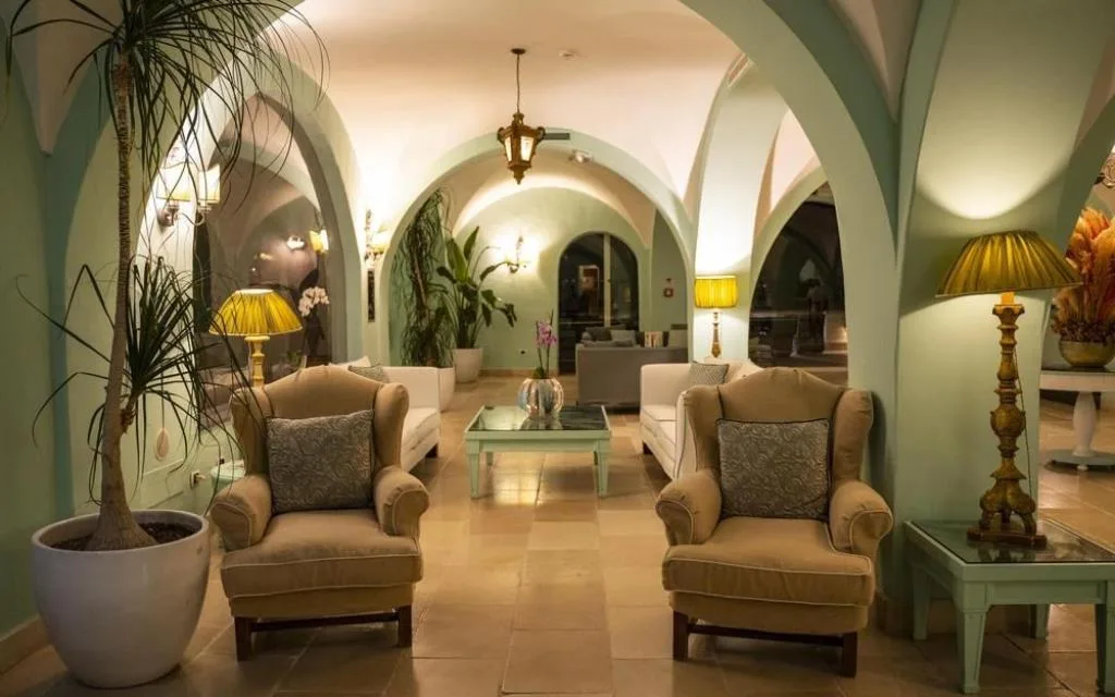 Elegante lounge interna con soffitti a volta verdi, poltrone e illuminazione soffusa