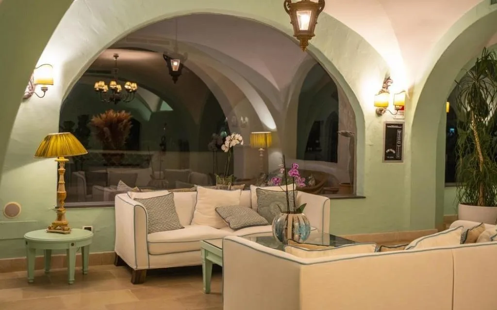Salotto interno con divani bianchi, archi verdi e lampade dorate d'atmosfera