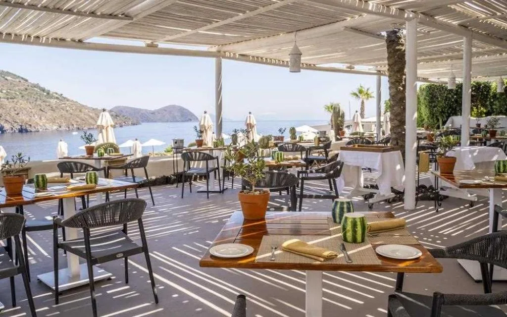 Terrazza ristorante coperta con pergolato e tavoli apparecchiati vista mare