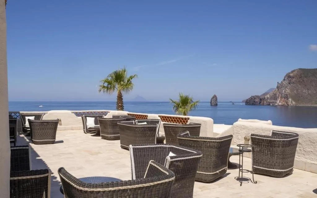 Terrazza panoramica con poltrone in vimini, palme e vista sul mare e le isole